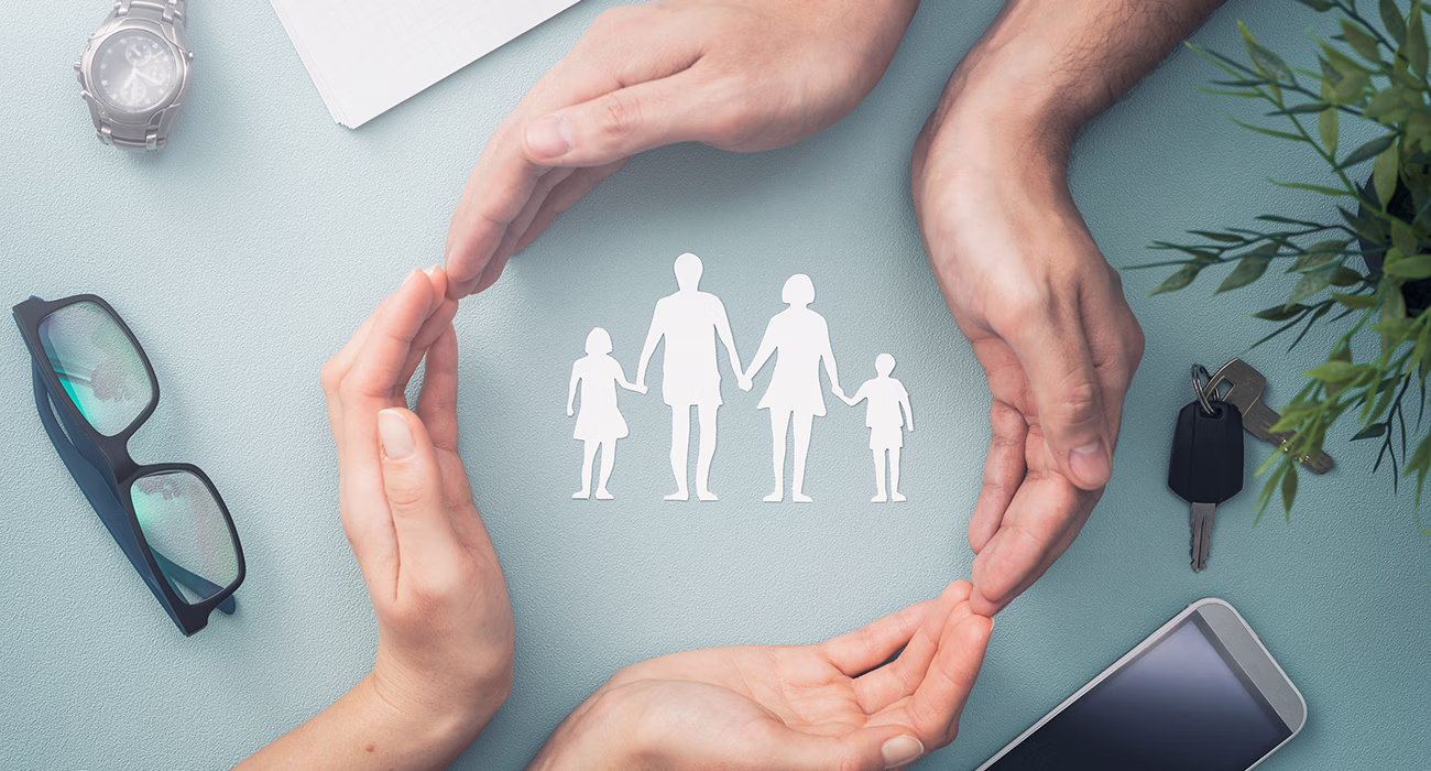 Hands with cut out paper silhouette on table. Family care concept