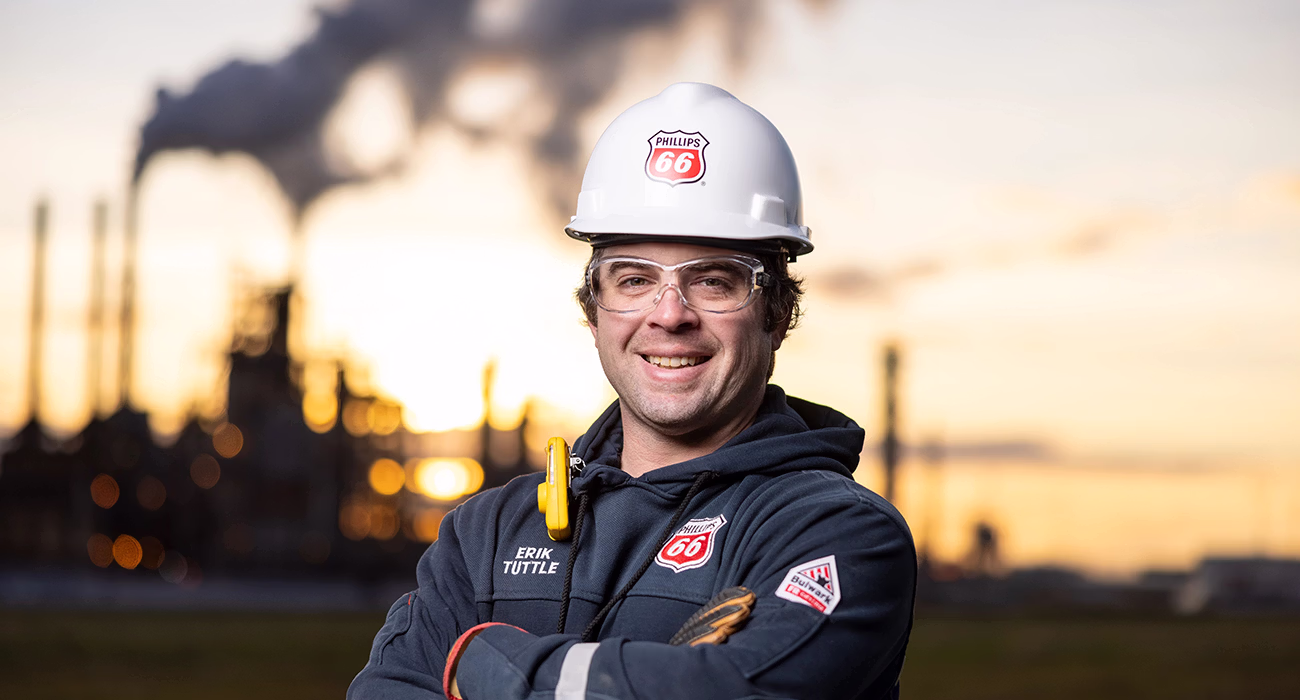 Male Phillips 66 worker standing in front of a refinery
