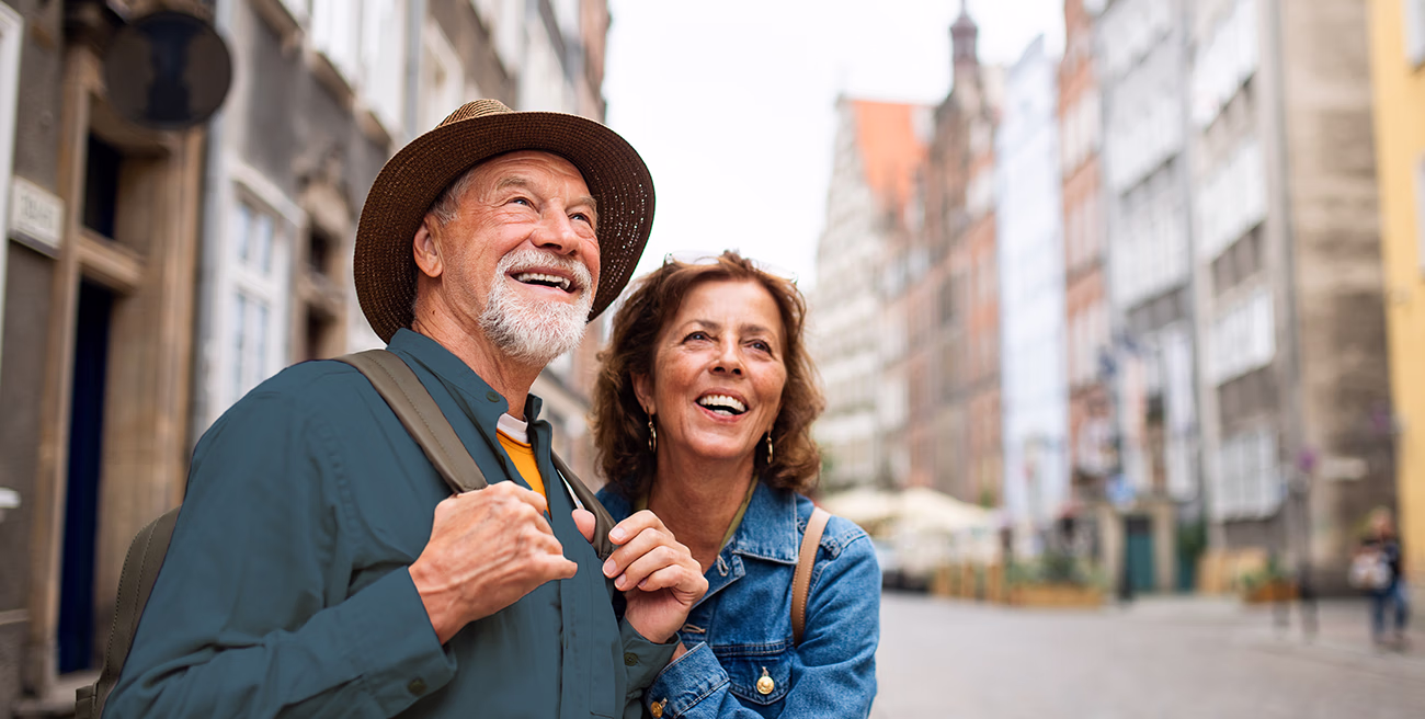 A portrait of happy senior couple tourists outdoors in historic town