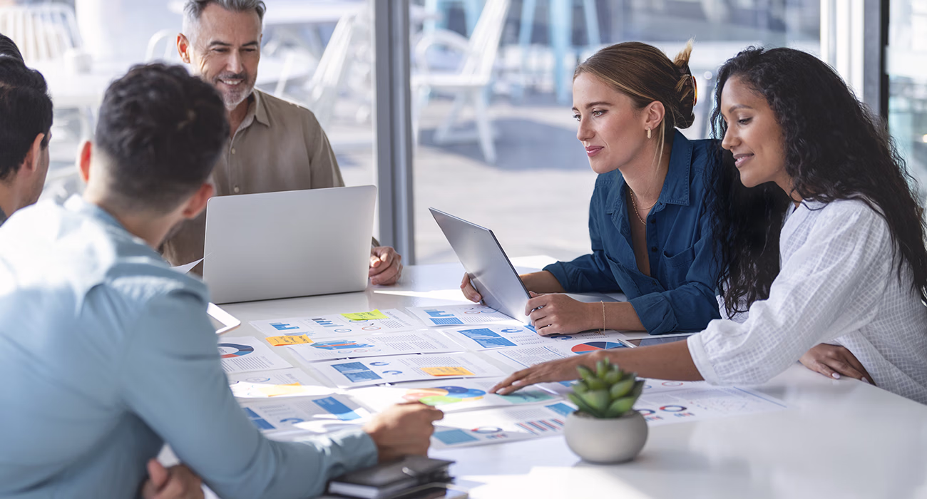 Multi racial diverse group of people working with Paperwork on a board room table at a business brainstorm, presentation or seminar