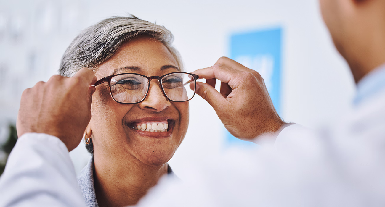 smile and woman with prescription glasses, optician and helping client with product