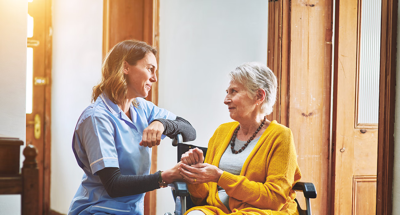 Close up of nurse and senior woman making heart shape with hands during a home visit